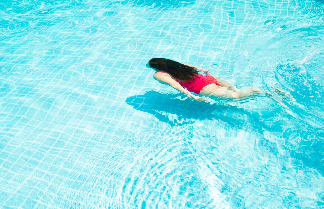 Woman Diving into the natural salt water pool at Palm Tree Health Spa, Luang Prabang, Laos